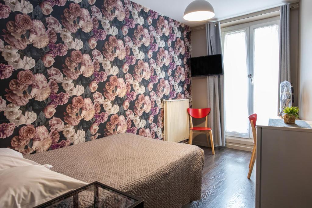 a bedroom with a floral wall with a bed and a red chair at Grand Hôtel De Paris in Paris