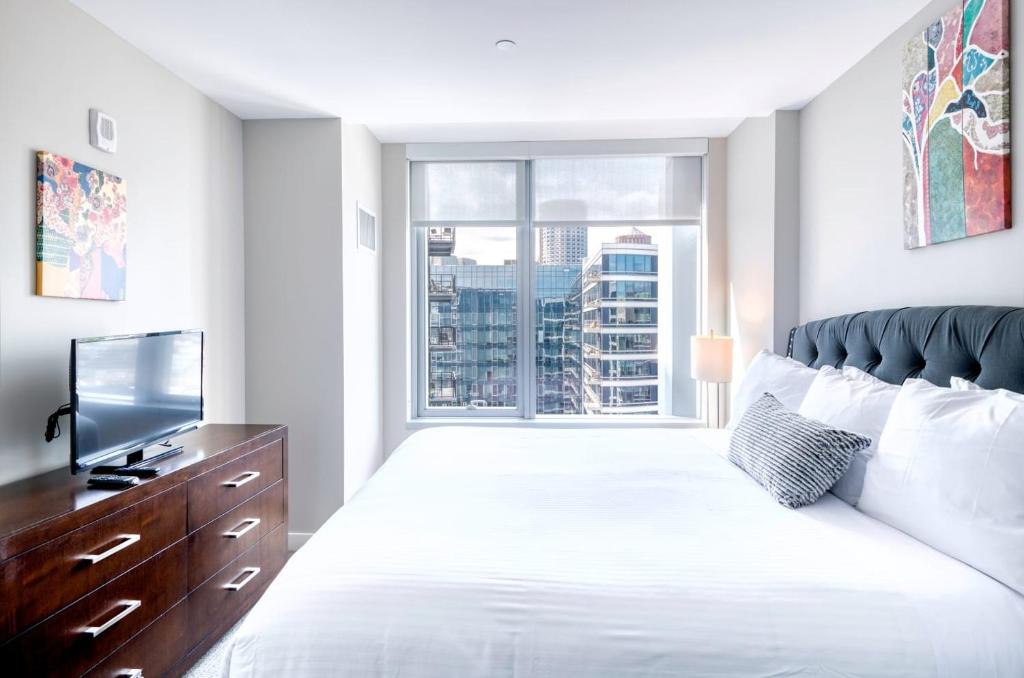 Un dormitorio con una cama con televisión y una ventana. en Modern Apt with Water Views, en Boston