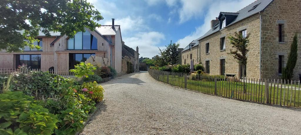 a gravel road between two houses with a fence at Les Grands Gîtes de Cancale, gîtes de charme avec jacuzzi in La Coudre