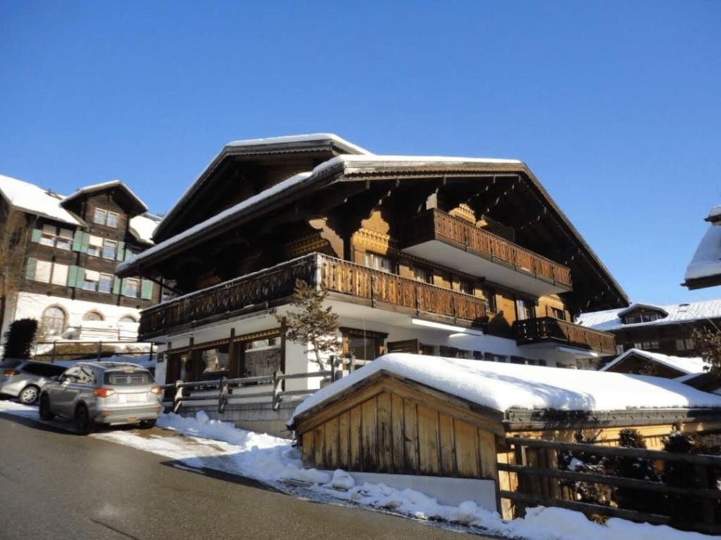 un grande edificio in legno con neve sul terreno di South Facing Family Chalet in Saanen Village a Gstaad