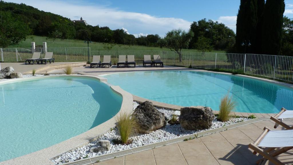 une piscine avec des chaises et des rochers dans une cour dans l'établissement Villa Adhémar 20 personnes, à La Garde-Adhémar