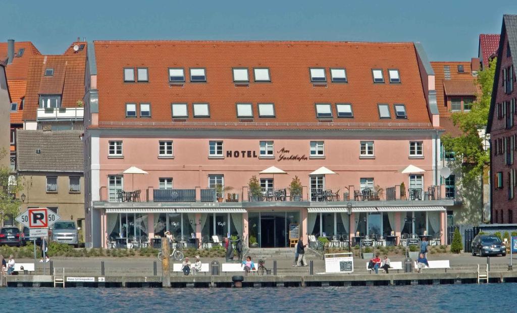 a large pink building next to a body of water at Hotel Am Yachthafen in Waren