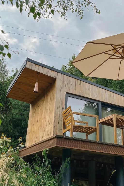 a house with two chairs and an umbrella at hOMM domek nad jeziorem in Stryszów