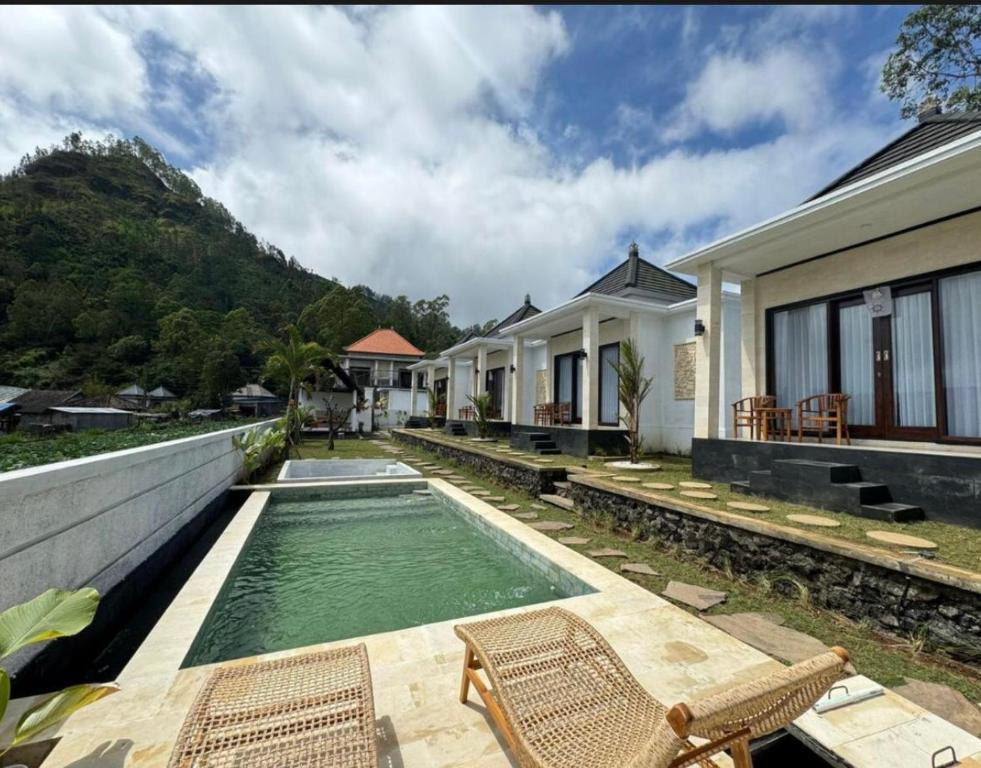 a swimming pool with chairs and a house at Volcano cottage bali in Kubupenlokan