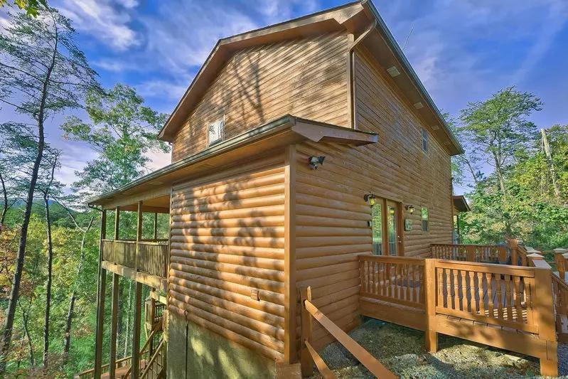 a wooden cabin with a deck in the woods at Private Paradise #2810 in Pigeon Forge