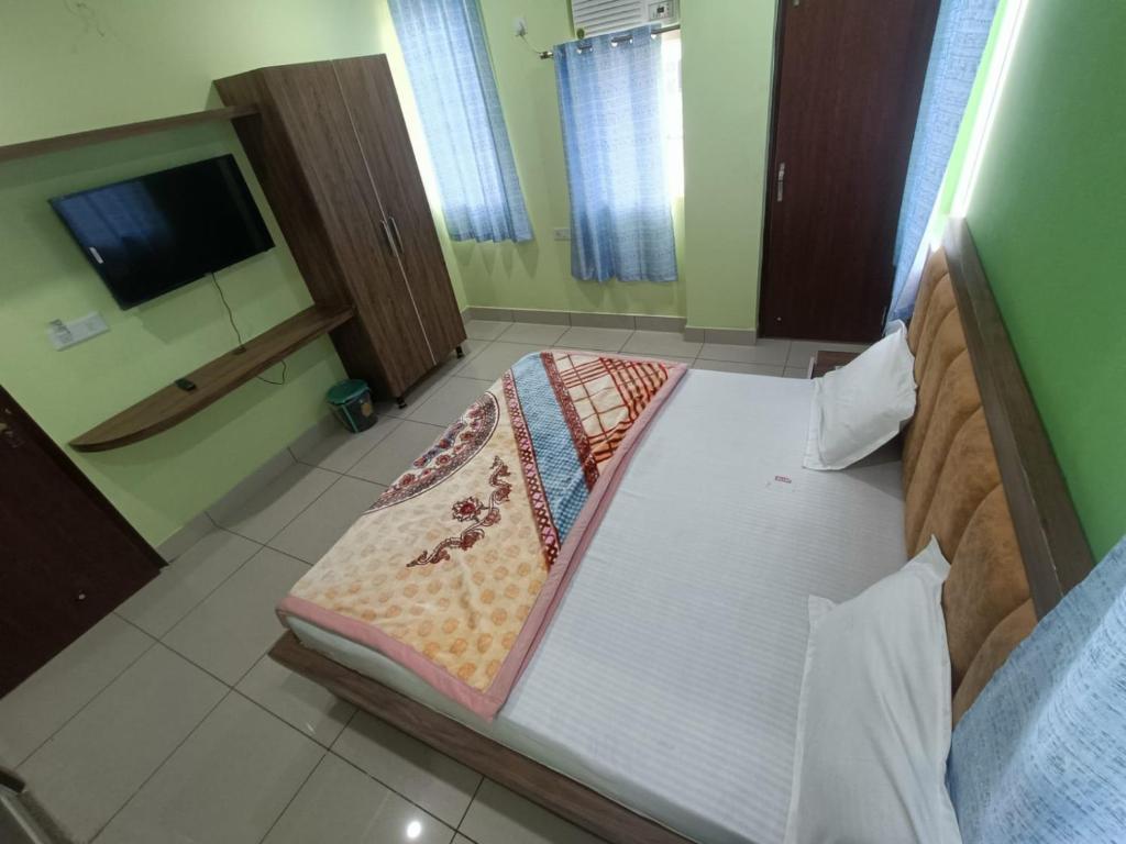 Cette chambre comprend un grand lit et une télévision. dans l'établissement Om hotel, à Rohtak