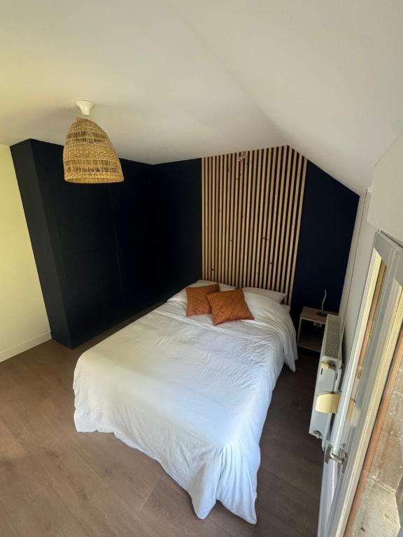 - une chambre avec un lit blanc et un mur noir dans l'établissement Gîte saint Bernard, à Sedan