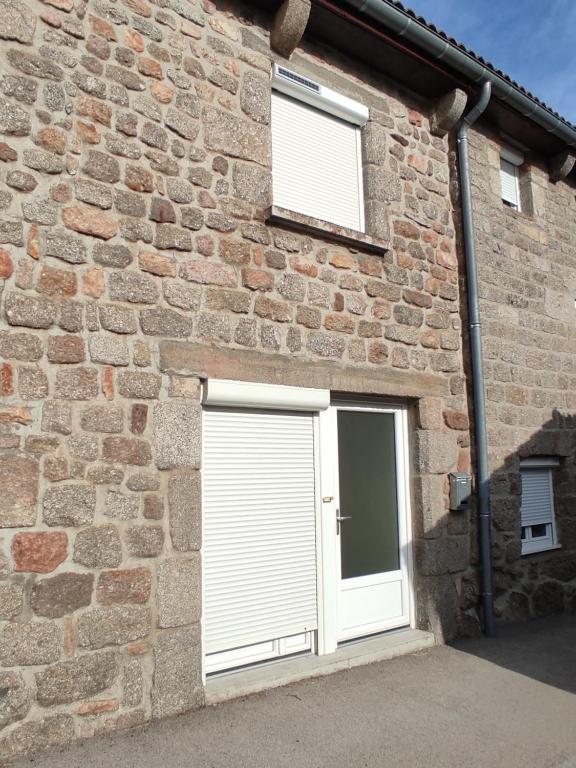 a brick building with two garage doors and two windows at Appartement à la campagne in Venteuges