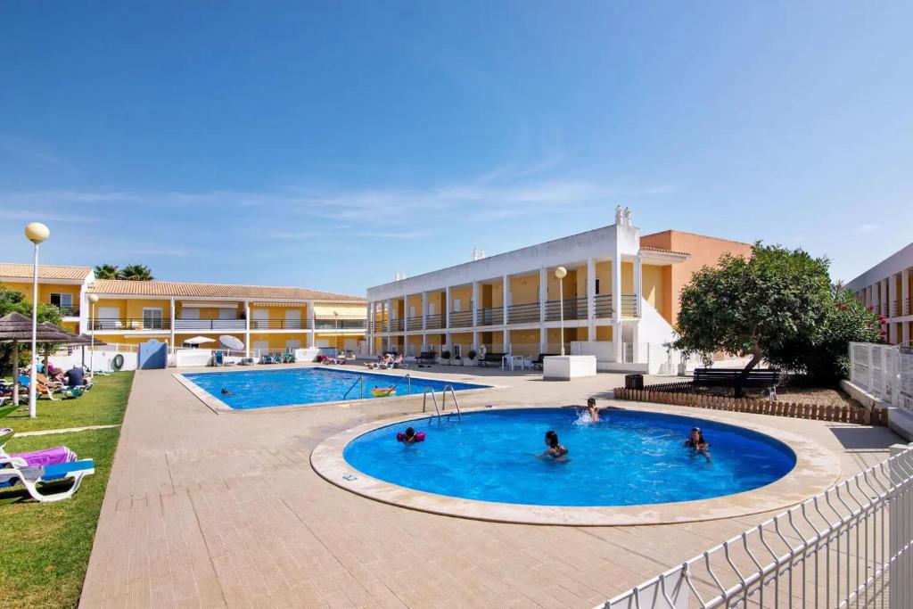 un groupe de personnes dans une piscine en face d'un bâtiment dans l'établissement T2 Encosta São José by Gabi Miguel, à Guia