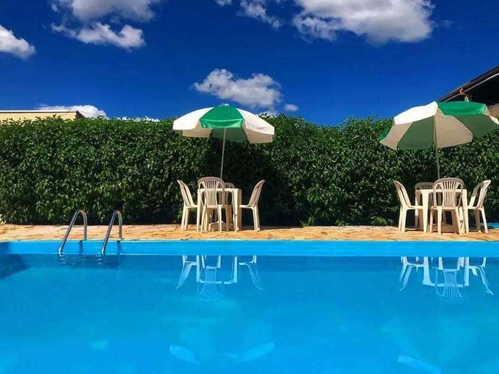 a group of chairs and umbrellas next to a swimming pool at Hotel Turismo Ltda in Chapada dos Guimarães
