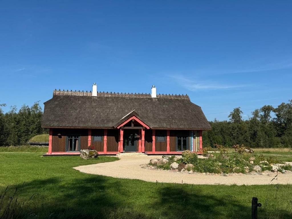 ein rotes Haus mit schwarzem Dach auf einem Feld in der Unterkunft Ülase Riverside Lodge, Rural Retreat for 20 Guests, Private Smoke Sauna Available, Estonia in Lohu