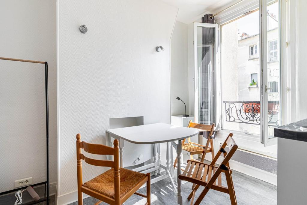 une salle à manger avec une table et des chaises et une fenêtre dans l'établissement GuestReady - Studio Lumineux et Charmant pour Deux, à Paris