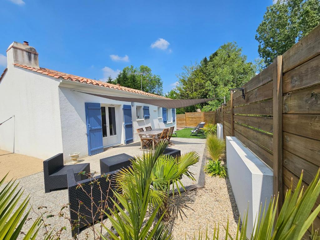 ein kleines weißes Haus mit einem Holzzaun in der Unterkunft Charmante Maison à 500m de la plage in La Tranche-sur-Mer