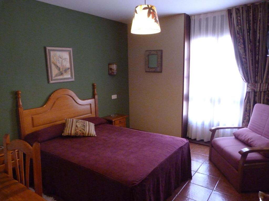 a bedroom with a bed and a couch and a window at Hotel Mestas in Arenas de Cabrales