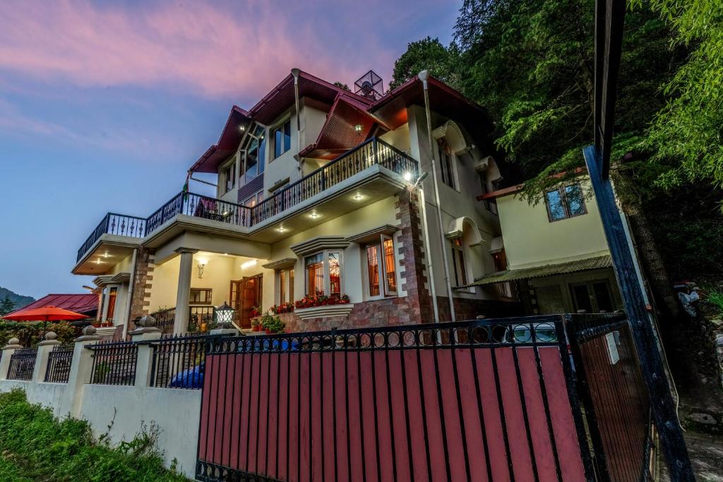 a house with a red fence in front of it at ELIVAAS 3 BHK with Entertainment lounge - The Meadow in Nainital