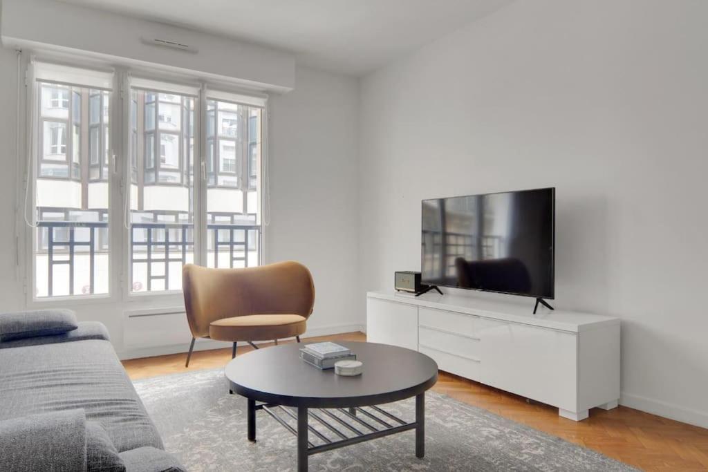 un salon avec un canapé et une télévision dans l'établissement Sublime appartement avec Parking Paris 17 Wagram, à Paris