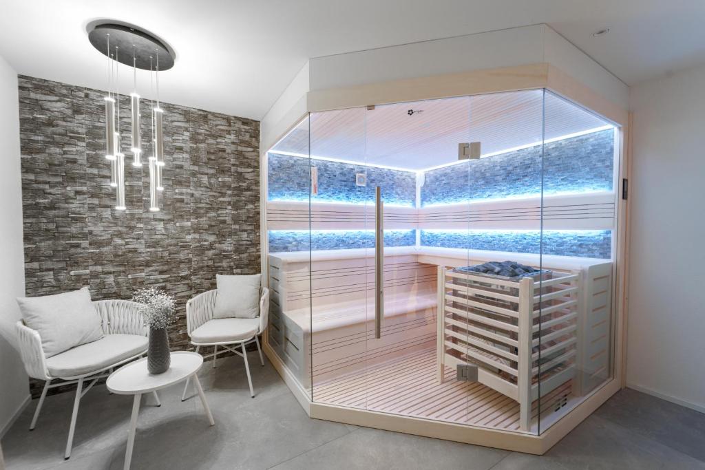 a room with a glass shower with a table and chairs at Privat-SPA mit Whirlpool und Sauna für 5 Personen! in Winterthur