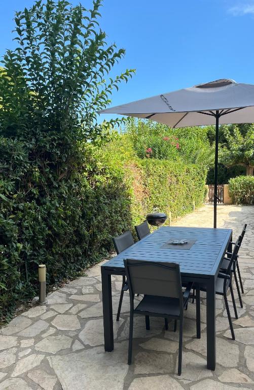 une table et des chaises bleues avec un parasol dans l'établissement Calme et confort en rez-de-jardin, à La Londe-les-Maures