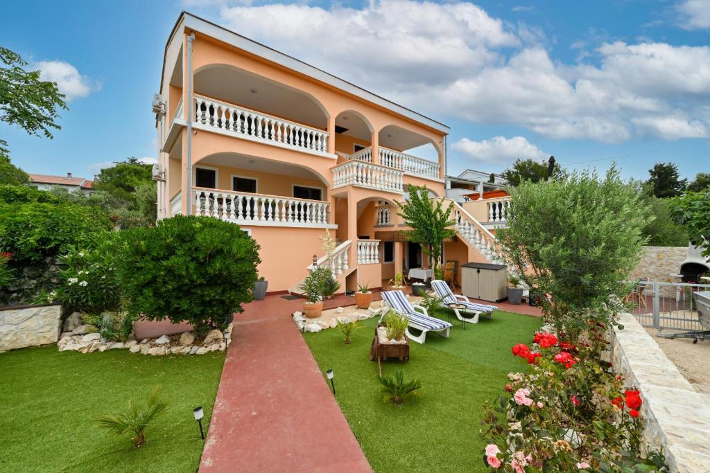 una grande casa con un cortile con sedie e fiori di Villa Schubert a Novalja (Novaglia)