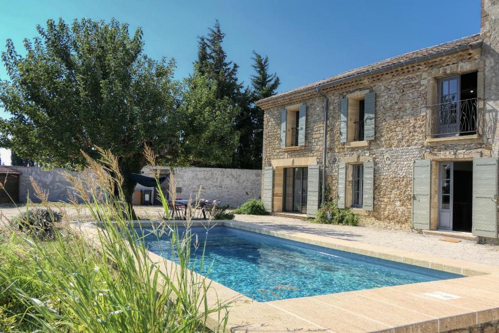- une piscine en face d'une maison en pierre dans l'établissement Sous le mûrier - Mas Provençal au coeur des vignes, à Travaillan