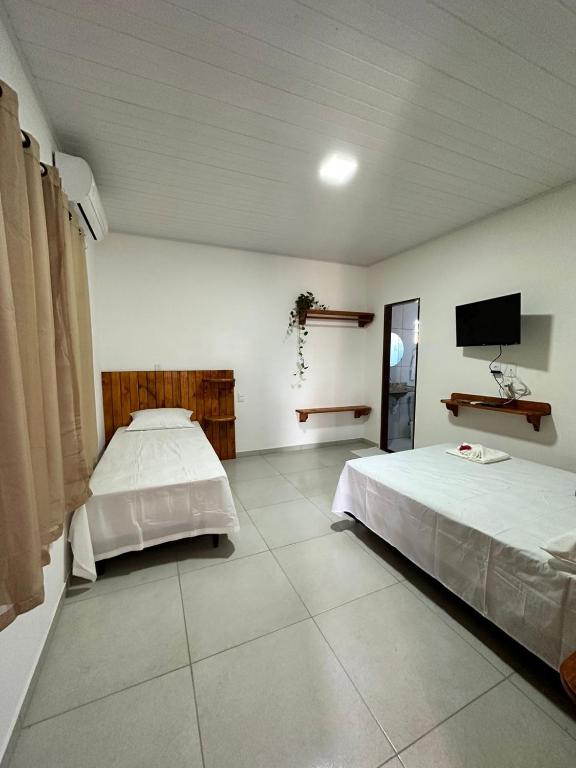 a bedroom with two beds and a flat screen tv at Vento Leste Suites in Flecheiras