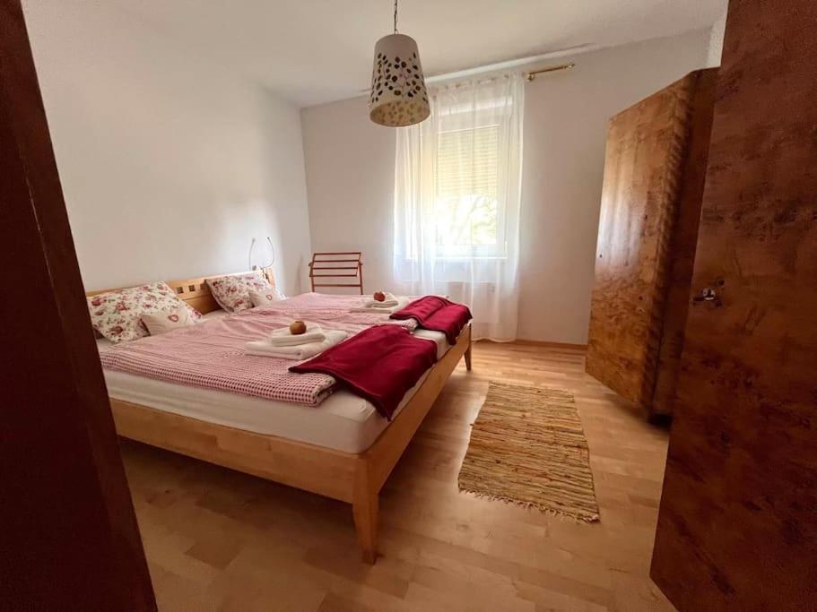 a bedroom with a bed with red sheets and a window at Appartment Weitblick in Eisenstadt