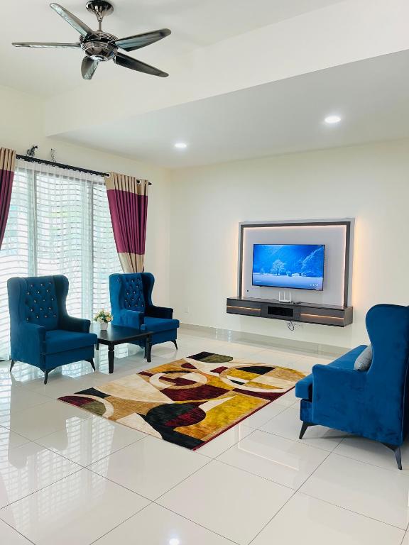 a living room with two blue chairs and a tv at Sofea Mutiara Homestay Ipoh in Ipoh