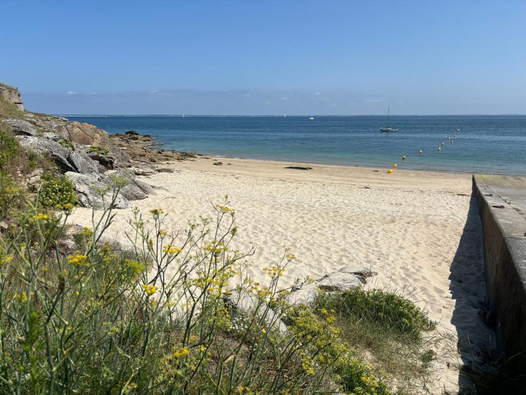 une plage de sable avec un bateau dans l'eau dans l'établissement Appartement spacieux et clair proche des plages de la baie, à Quiberon