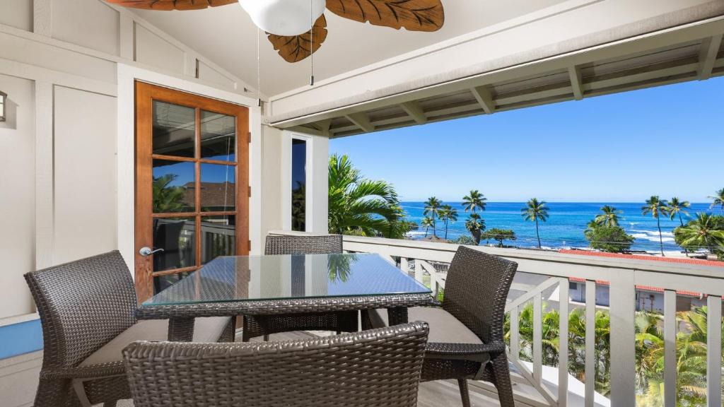 Una mesa y sillas en un balcón con vista al mar. en Alii Cove Y22, en Kailua-Kona