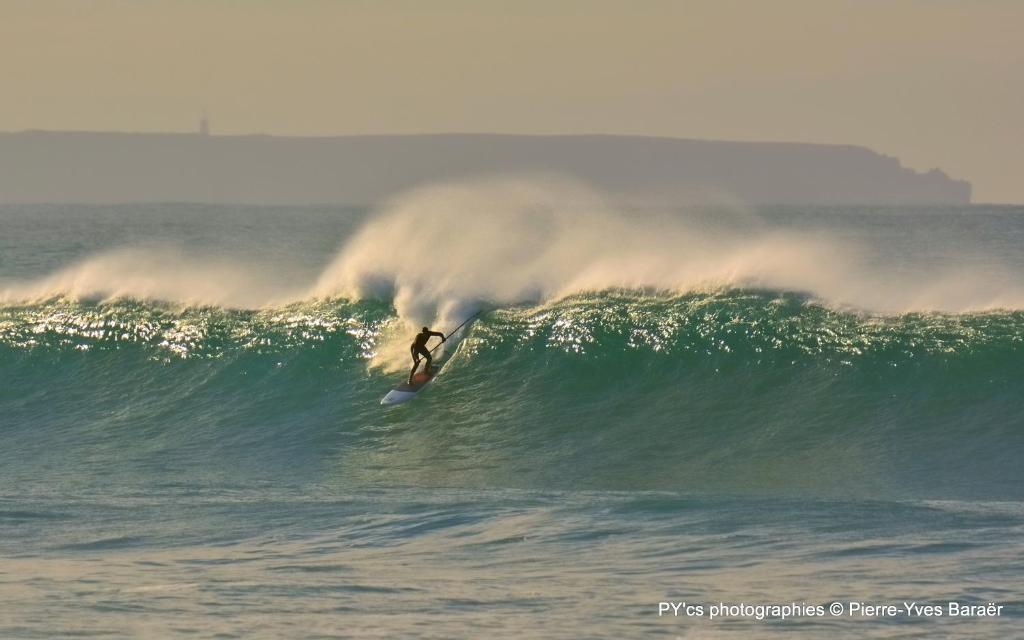 a person riding a wave on a surfboard in the ocean at Gite de la Baie - Morgat in Crozon