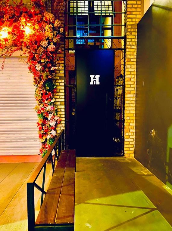 a bench in front of a black door with flowers at H70-Hostel 70 FLORIPA in Florianópolis