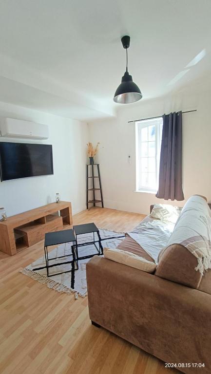 un salon avec un canapé et une télévision à écran plat dans l'établissement La nuit Fréventine, à Frévent