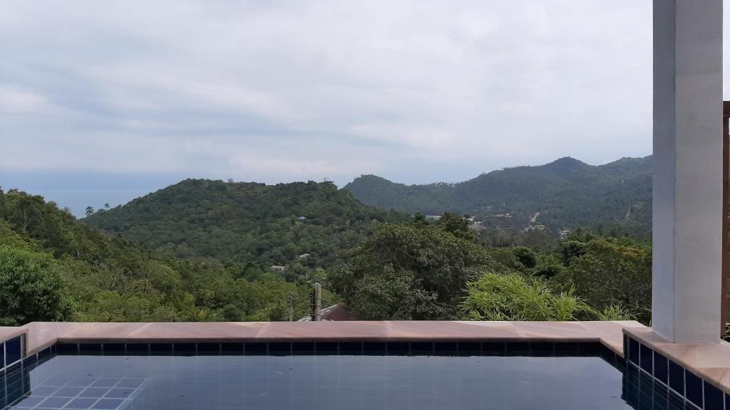 a swimming pool with a view of mountains at Than Prawet Waterfall villa in Thong Nai Pan Noi