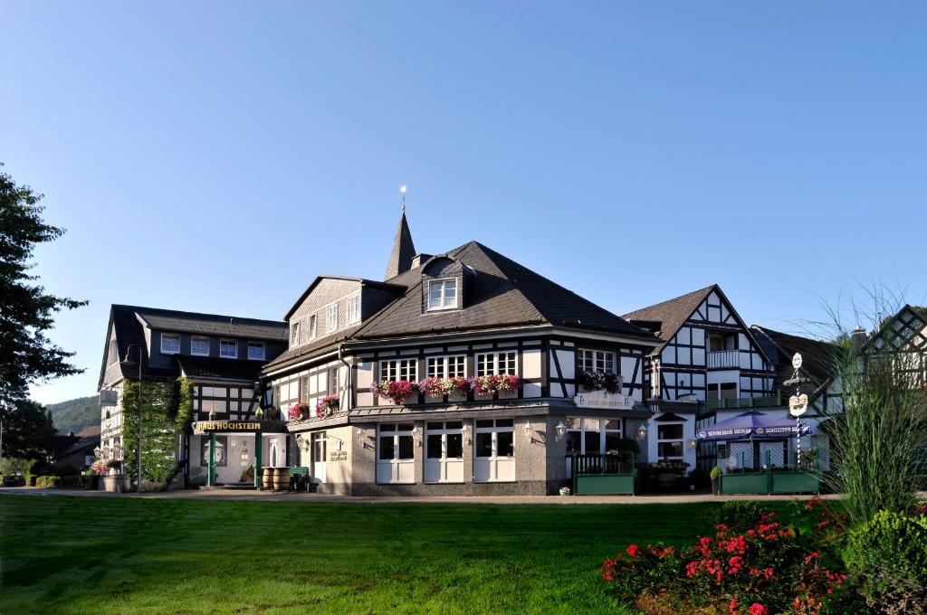 een groot huis met bloemen in de voortuin bij Landidyll Hotel Haus Hochstein in Wenholthausen