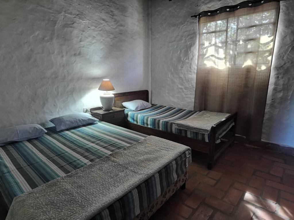 a bedroom with two beds and a window with a lamp at Hostel Ysapy en Piribebuy - Paraguay in Piribebuy