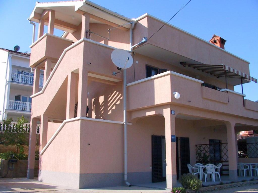 a pink building with a balcony and a table at Apartment Kornic 3 in Kornić
