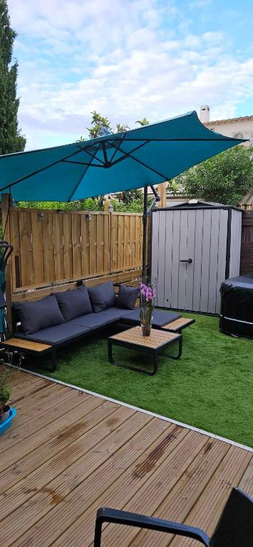 un parasol bleu sur un canapé et une table dans l'établissement residence eureka T2 proche du camp, au Cap d'Agde