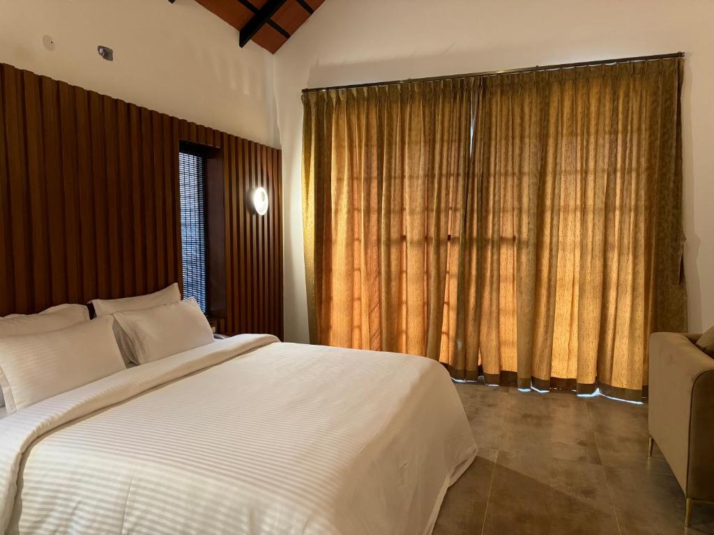 una camera da letto con un grande letto bianco e una finestra di The Caligo resort coorg a Madikeri