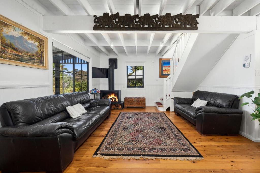 sala de estar con sofás de cuero negro y chimenea en Braeside Cross, en Blackheath