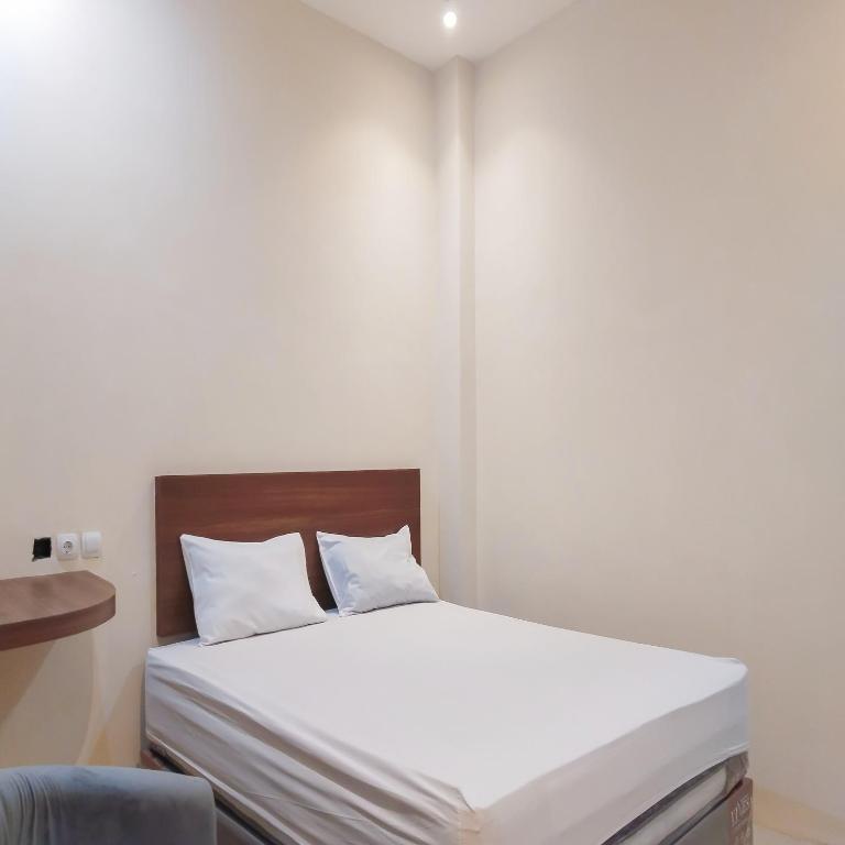 a bed with white sheets and pillows in a room at RedDoorz near Plaza Asia Tasikmalaya in Padayungan