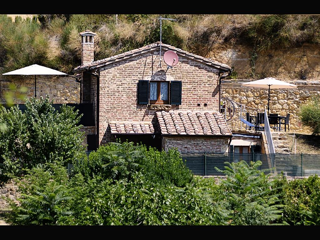 Casa de ladrillo con ventana, mesa y sombrilla en La Casina Toscana en Montepulciano