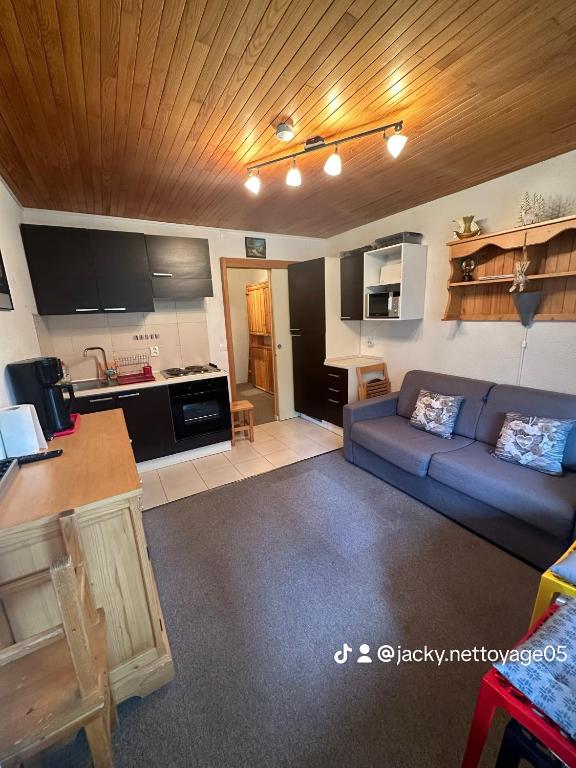 un salon avec un canapé bleu et une cuisine dans l'établissement Chez Martine, à Vars