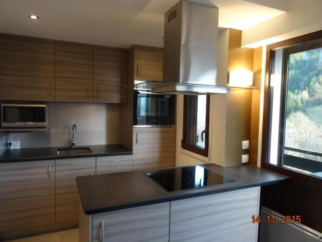 une cuisine avec des armoires en bois, un évier et une fenêtre dans l'établissement Le Tavaillon, au Grand-Bornand