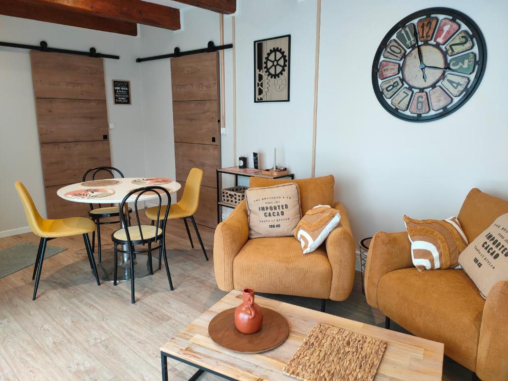 a living room with furniture and a clock on the wall at Le PTit Atelier, Appartement cosy à Champagnole in Champagnole