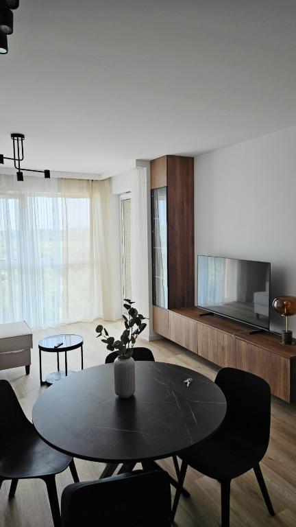 a living room with a table and chairs and a tv at Nova Letnica Sea Apartaments in Gdańsk Letnica