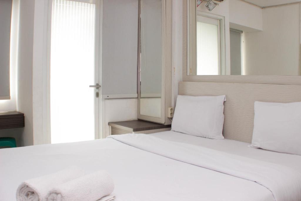 a bedroom with a large white bed with a mirror at Cozy and Warm Studio at Grand Sentraland Karawang Apartment By Travelio in Karawang
