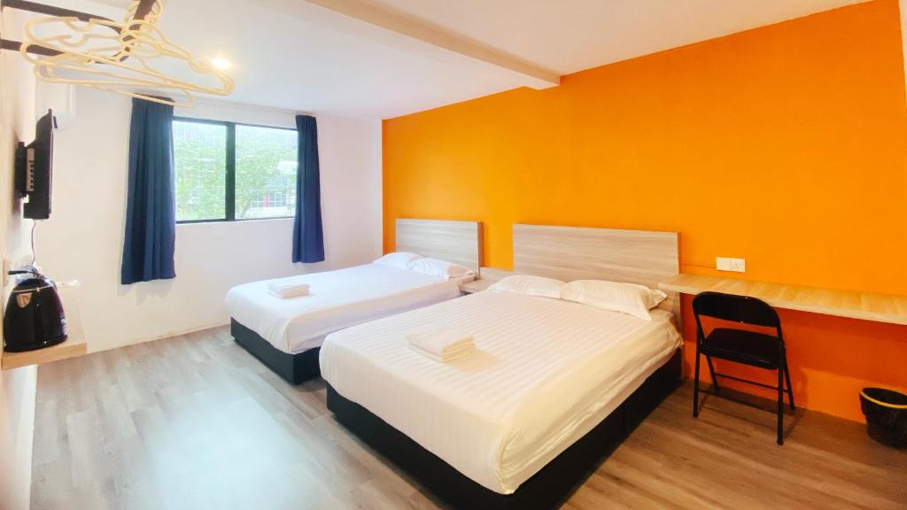 two beds in a room with an orange wall at Hi-Inn in Miri