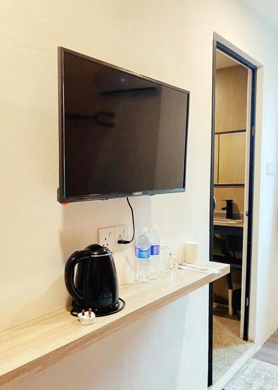a flat screen tv on a wall with a black purse at Hi-Inn in Miri