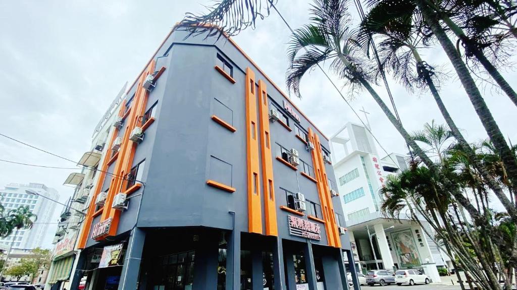 a building with orange doors and palm trees on a street at Hi-Inn in Miri