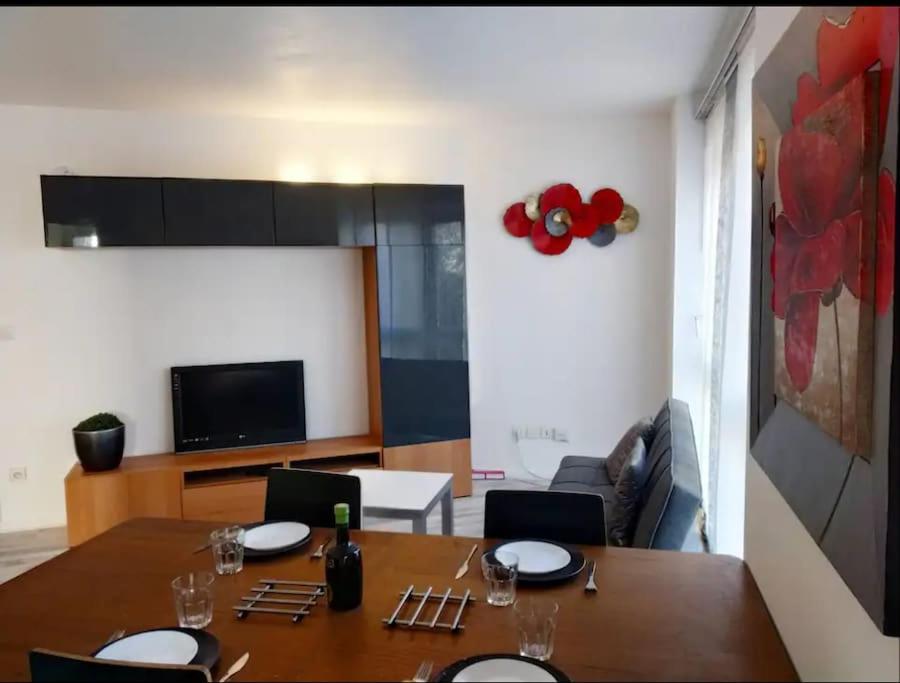 a dining room with a table and a room with a couch at Superb modern apartment in Clichy